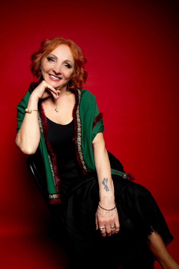 moteris sypsosi sededama su zaliu svarku, uz jos raudonas fonas