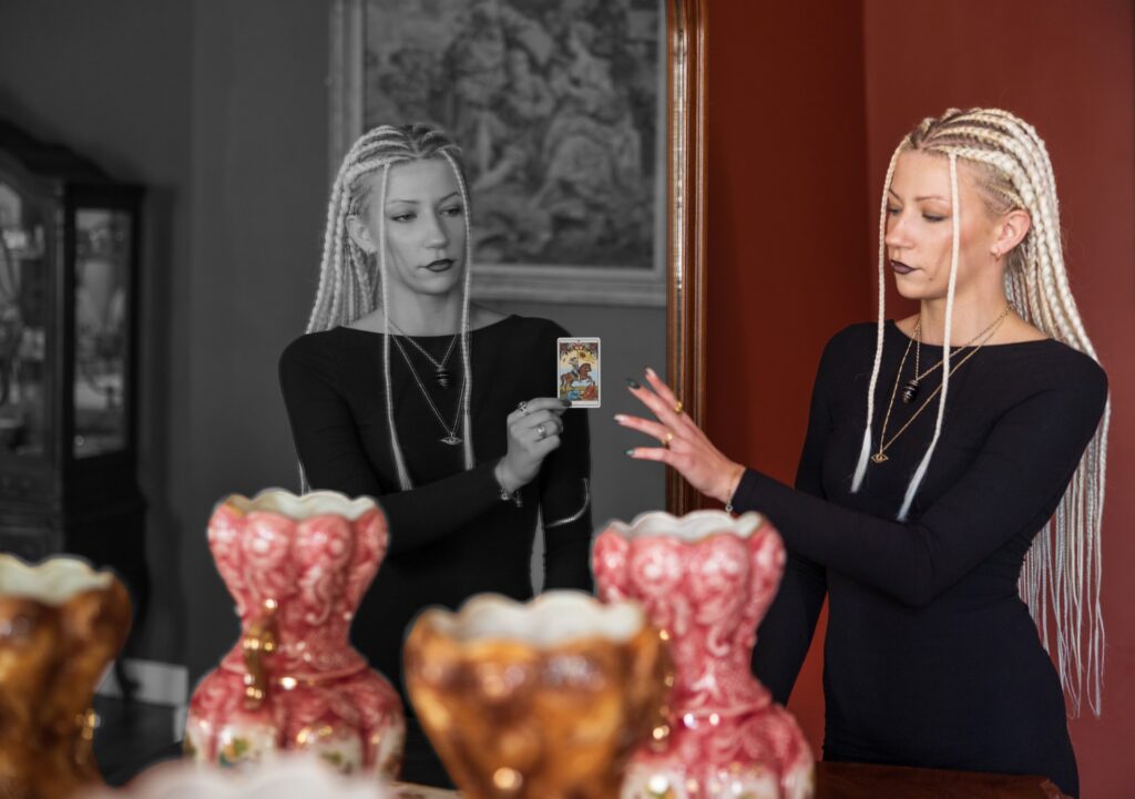 moteris ziuri i veidrodi kur jos atspindys ir laiko taro kortas