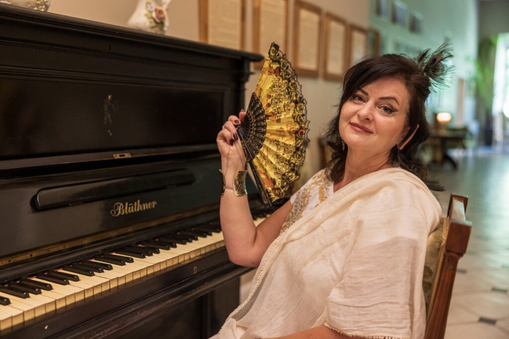 moteris su veduokle sedi prie pianino