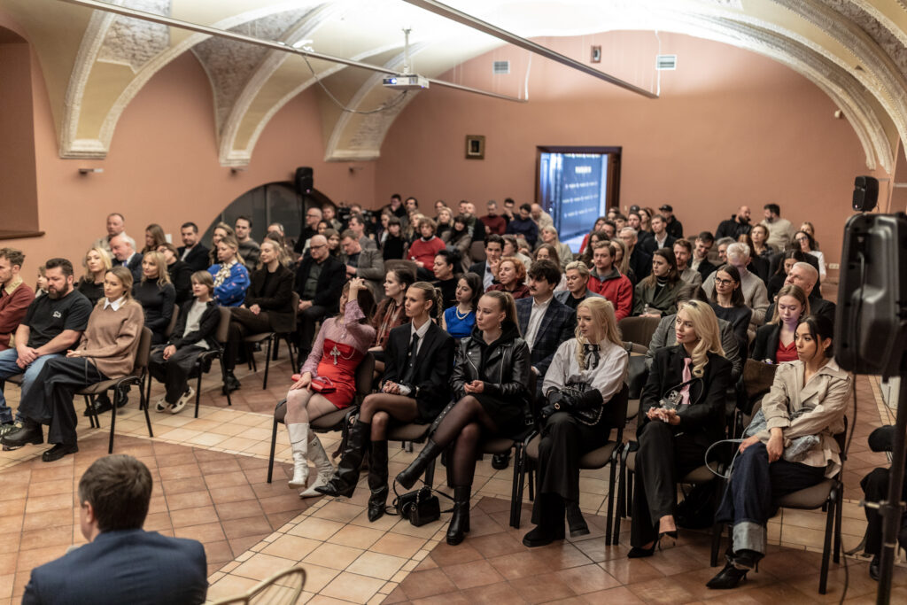 daug zmoniu sedi ant kedziu ir ziuri i ekrana