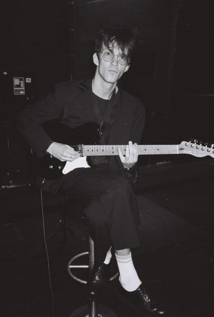 vyras su gitara juodam baltam fone